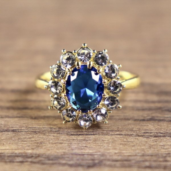 Damenring, goldfarben, Hauptstein Blau mit kleinen weißen Steinen umkreist