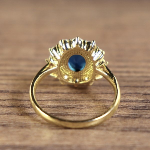 Damenring, goldfarben, Hauptstein Blau mit kleinen weißen Steinen umkreist
