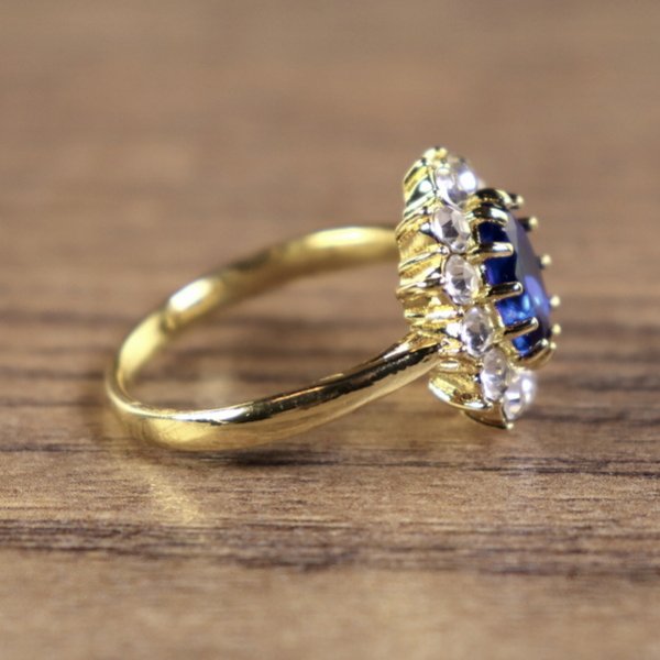 Damenring, goldfarben, Hauptstein Blau mit kleinen weißen Steinen umkreist